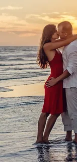 Couple embraces at sunset on a beach with waves gently touching their feet.