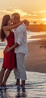 A couple embraces on the beach during a vibrant orange sunset.