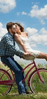 Couple riding bicycle in a field with a clear blue sky.