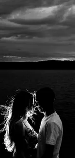 Black and white silhouette of a romantic couple by the water.