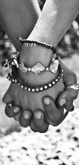 Black and white image of hands holding with bracelets.