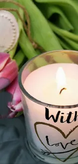 Candle with "With Love" text beside pink tulips.