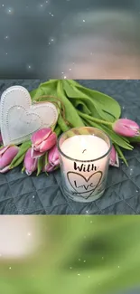 Candle with heart and pink tulips on a gray background.