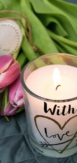 Romantic scene with a candle, pink tulips, and a heart on a quilt.