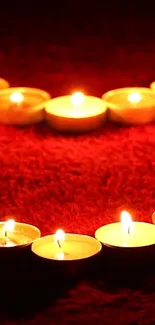 Heart shaped candle arrangement on red background.