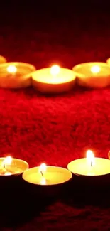 Romantic heart-shaped candle arrangement on red background.