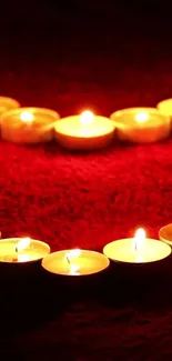 Heart-shaped candle arrangement on red background.