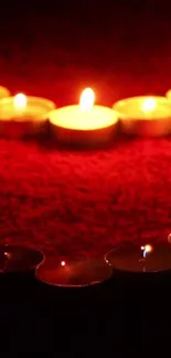 Romantic candlelit wallpaper with glowing candles on a red background.