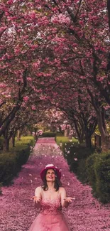 Woman in pink dress on cherry blossom path, surrounded by petals.