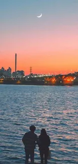 Couple admiring urban sunset with crescent moon and city skyline.