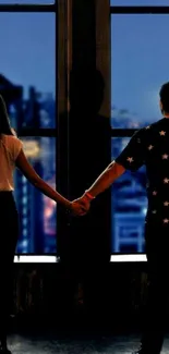 Couple holds hands overlooking a city skyline at night.