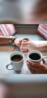 A romantic coffee date scene with hands holding across a table.