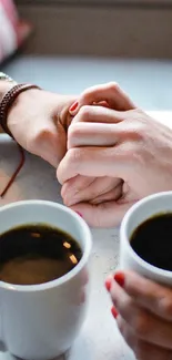 Romantic coffee date with hands held over table.