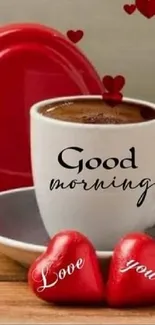 White cup with coffee, hearts, and "Good Morning" text on a wooden table.