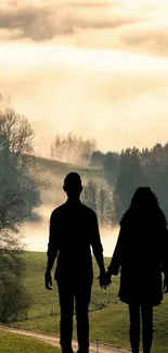 Silhouette couple holding hands in misty landscape.