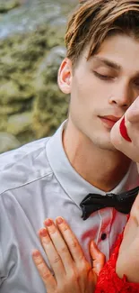 Romantic couple embracing on a rocky beach in vibrant red attire.