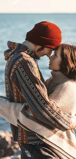 Couple embracing by the sea with rocky shore.