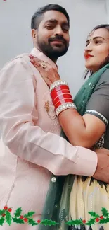 Couple embracing in traditional attire with festive holly border.