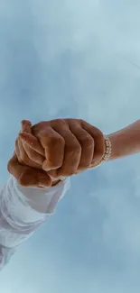 Couple holding hands under a bright blue sky.