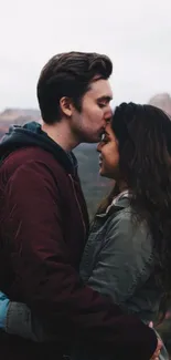 Romantic couple embracing in nature with a scenic backdrop.