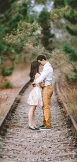 Romantic couple embracing on a scenic forest railway track.