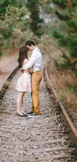 Romantic couple embracing on railway track in lush nature.