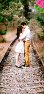 Romantic couple embraces on railway tracks with lush green surroundings.