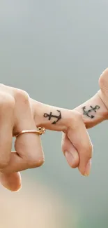 Two hands with tattoos gently intertwined in a romantic gesture.