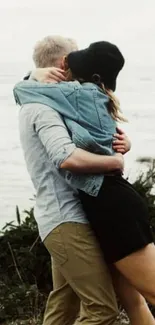 Couple embracing by the sea, surrounded by nature.