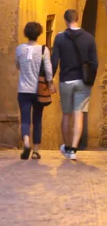 Couple walking on a cobblestone street at dusk, under warm yellow lighting.