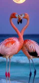 Two flamingos form a heart shape by the beach under a full moon.