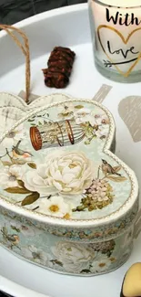 Heart-shaped floral box and love candle on decorative tray.