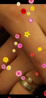 Vibrant floral overlay on hands with a ring on mobile wallpaper.