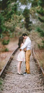 Romantic couple embracing on forest railway tracks wallpaper.