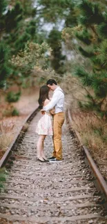 Couple embraces on forest railway track.