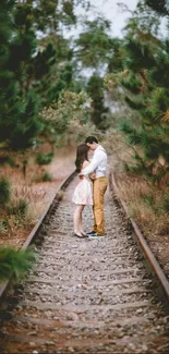 Romantic couple on forest railway tracks, surrounded by greenery.