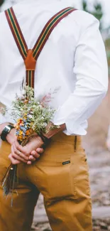 Man with bouquet behind back in outdoor setting.