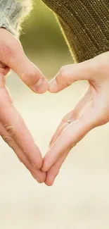 Mobile wallpaper of two hands creating a heart shape.