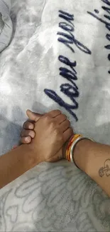 Couple holding hands on a light gray blanket.