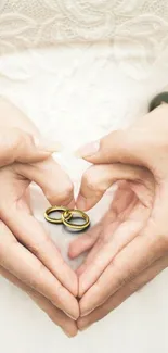 Romantic hands forming a heart with wedding rings in center.