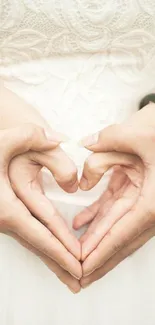 Hands forming a heart on a lace dress background, perfect for romance.