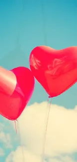 Heart-shaped balloons float in a clear blue sky with clouds.