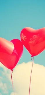 Two red heart-shaped balloons against a clear blue sky.