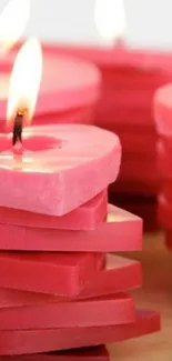 Heart-shaped pink candles stacked with flames on mobile wallpaper.