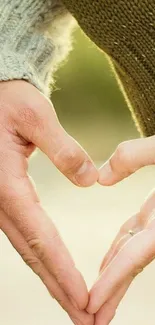 Two hands forming a heart shape against a soft, olive green background.