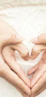 Intertwined hands forming a heart against a cream background.