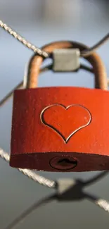 Red heart padlock hanging on metal fence.