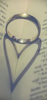 Ring creating a heart-shaped shadow on a book page, evoking romance and elegance.