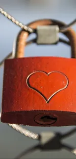 Heart-shaped red padlock on a wire fence, symbolizing love and connection.