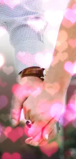 Couple holding hands with heart bokeh effect in pink hues.